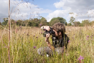 Boy taking photograph in meadow