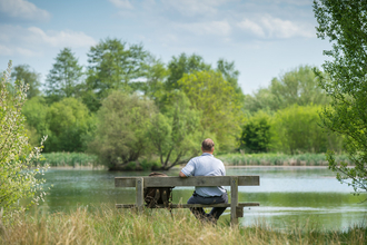 Man sitting on bench looking at lake