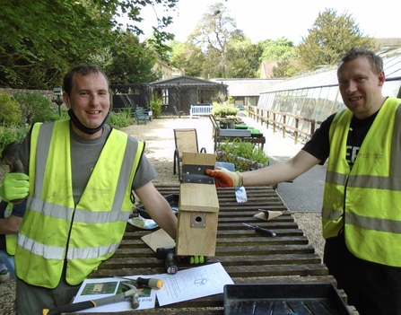 Two people holding a bird nest box