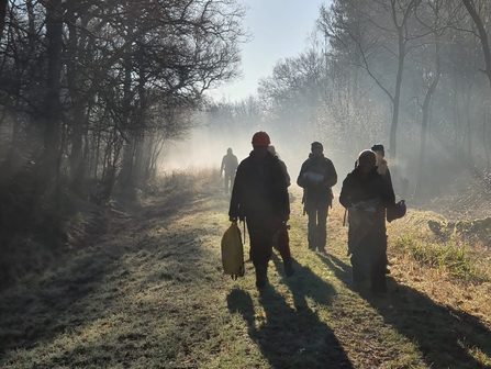People walking through woodland on a misty morning