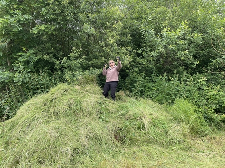 Person standing on top of a large pile of grass cuttings