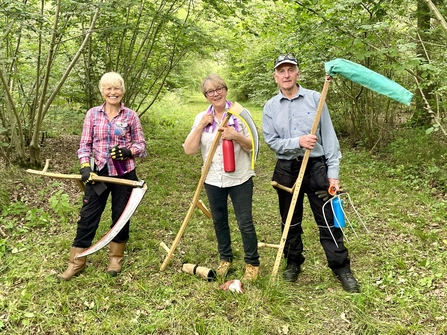 Three volunteers holding scythes