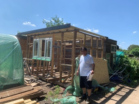 Man standing in front of a shed frame that's being built